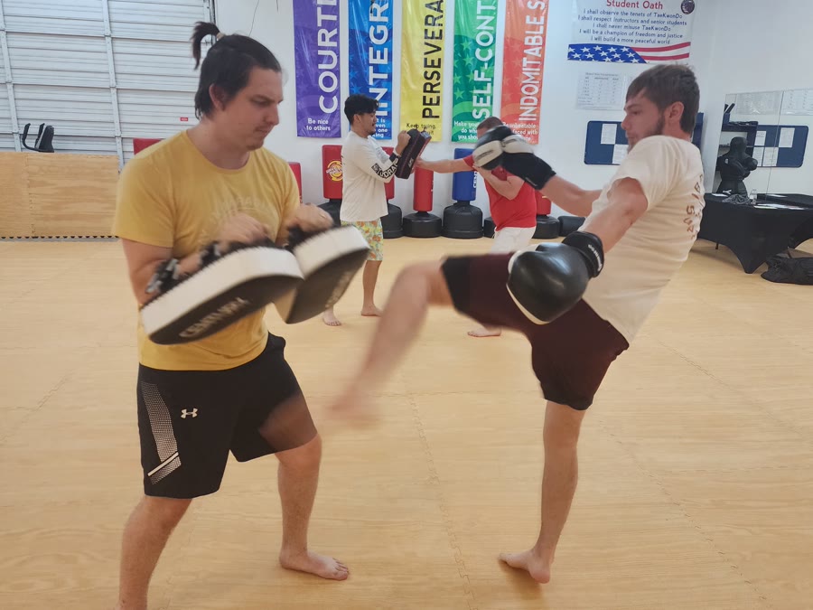 An adult kicking Thai pads during a Kickboxing class at Bares Taekwondo Fitness in Tyler, TX